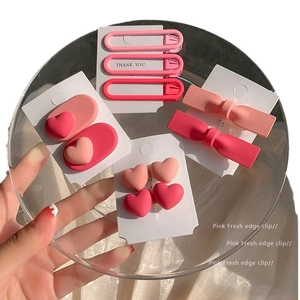 Pink matte heart and bow hair clip set displayed in a glass tray on white fabric