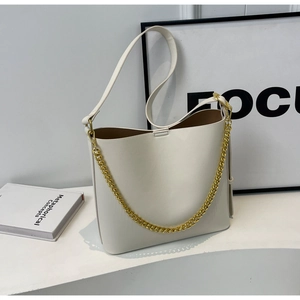 Detail of white PU leather tote bag featuring a decorative gold chain and bucket silhouette