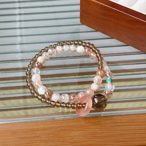 Detail shot of natural crystal beaded bracelets on wooden and striped glass surfaces