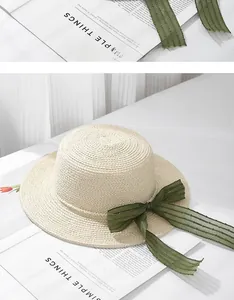 Detail of summer straw boater hat featuring green chiffon ribbon and pearl edge accents
