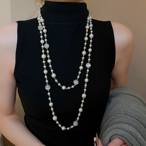 Détail d'un collier multicouche en perles et œil-de-chat sur un col roulé noir