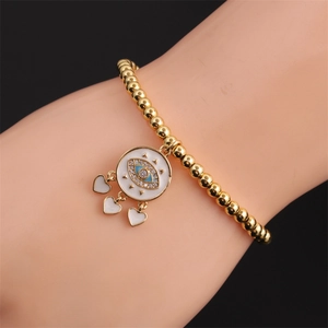 Close-up of a gold-plated beaded bracelet featuring an evil eye charm and three heart drops