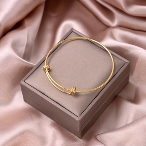 Detailed view of golden knot-style open bangle bracelet on luxury velvet packaging