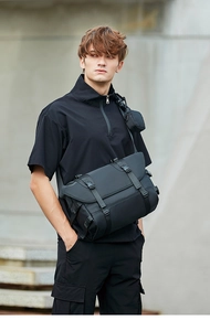 Detail view of the buckle closure and waterproof nylon material of the black messenger bag