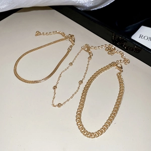 Détail de trois chaînes dorées avec maille serpent, billes et maille gourmette élégante