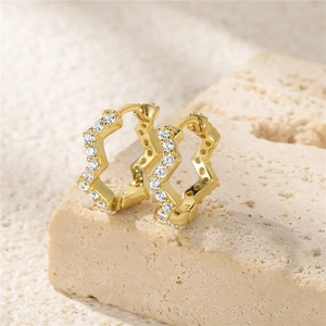 Macro detail of gold wavy earrings set with sparkling white cubic zirconia on stone
