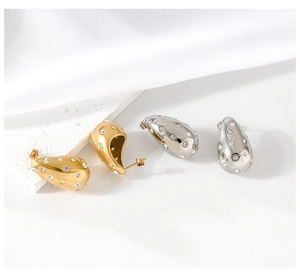 Detailed view of teardrop earrings with white zircon accents on silk background