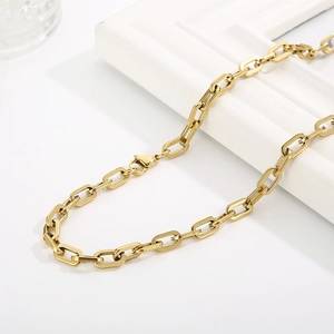 Close-up of golden stainless steel paperclip chain with lobster clasp on white decor