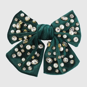 Dettaglio del fermaglio a fiocco in velluto verde scuro con strass e perle eleganti