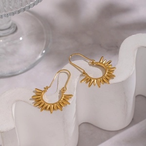 Elegant gold sunburst drop earrings in stainless steel on white geometric background