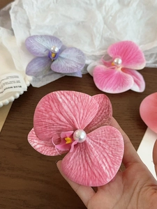 Close-up of orchid flower hair clip with realistic fabric petals and pearl center