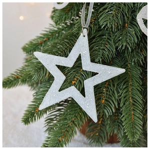 Close-up of white glitter star ornament hanging on a Christmas tree with warm lights