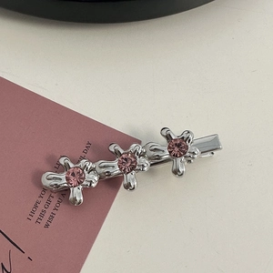 Macro detail of silver alloy hair clips featuring pink rhinestone flower embellishments