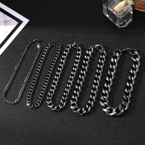 Five black stainless steel Cuban link bracelets in various widths on a textured surface