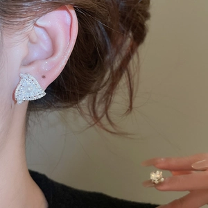 Close-up of elegant triangular pearl earrings with zircon on silver base worn by a model