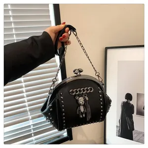 Detail of black leather shell bag featuring silver rivets and a crystal bear charm