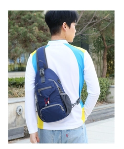 Detailed back view of a blue nylon outdoor chest bag with mesh bottle pocket and headphone port