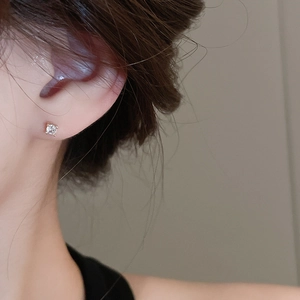 Close-up of minimalist cubic zirconia stud earrings shown on model ear for scale