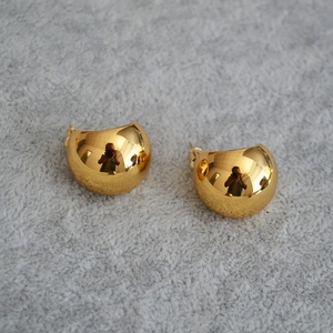 Detailed view of polished golden waterdrop earrings on textured fabric background