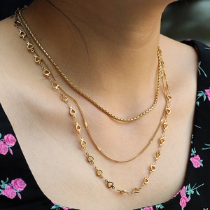 Detail of 18K gold plated titanium heart pendant with triple layer chain set on a model