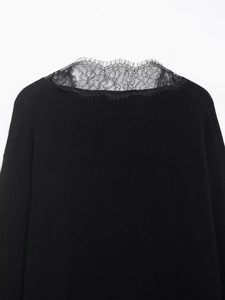 Close-up of intricate floral eyelash lace patchwork on black knit V-neck long sleeve top