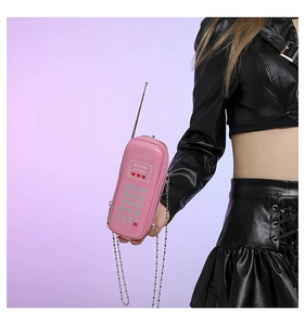 Détail du sac à bandoulière rose en forme de téléphone rétro porté par un mannequin Y2K