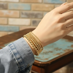 5-piece set of 18K gold plated bead stretch bracelets worn by a model in warm light