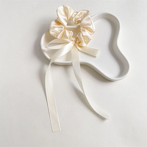 Detail of cream satin scrunchie with elegant long ribbons on a ceramic tray