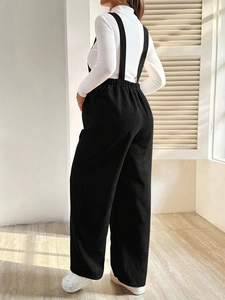 Detailed back view of black corduroy maternity overalls with adjustable waist and straps