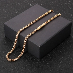 Macro view of golden stainless steel square pearl box chain on a black gift box stand