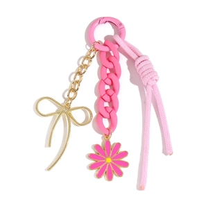 Détail de la corde tissée rose et du nœud doré avec charm fleur pour sac