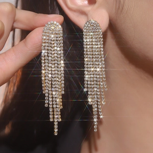 Close-up of luxury gold-plated long tassel earrings with sparkling rhinestones on model