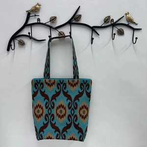 Detail of blue and brown geometric patterned tote bag hanging on a bird design metal hook