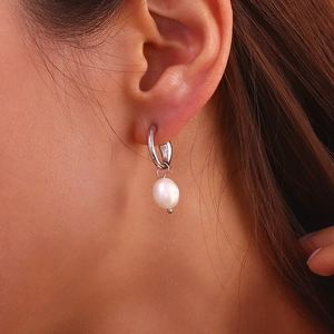 Macro detail of a 18K gold plated stainless steel hoop earring with a freshwater pearl drop