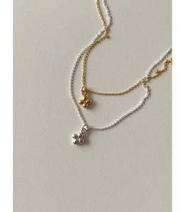 Gros plan d'un collier en argent 925 avec perles, croix et pendentif trèfle minimaliste