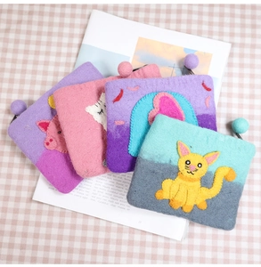 Detailed close-up of handmade felt coin purses with animal designs and colorful pom-poms