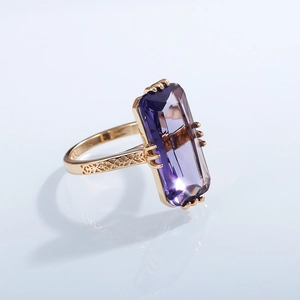 Macro shot of rectangular purple zircon gemstone with golden engraved ring band details