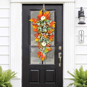 Autumn teardrop swag with white pumpkins and maple leaves hanging on a dark front door