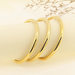 Macro detail of three 6mm polished gold stainless steel bangles with glossy finish