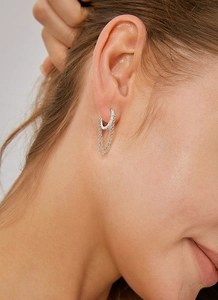 Close-up of silver tassel chain hoop earrings with micro-pave zircons on a female model