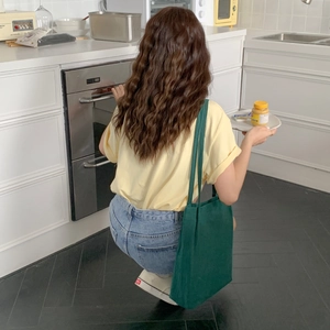 Lifestyle shot of a dark green washed cotton tote bag paired with casual summer outfit