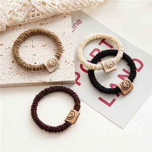 Set of four woven elastic hair ties with leather smiley face patches in neutral colors