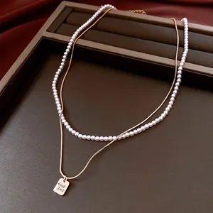 Collana a doppio strato con catena a serpente dorata, perle bianche e ciondolo Good Luck