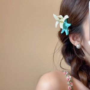 Detail of light blue starfish hair clip with white flower on a braided hairstyle
