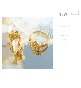 Detailed view of adjustable gold-plated fox rings on a reflective surface with lace