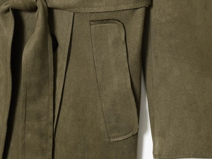 Detalle de gabardina verde oliva efecto ante con cinturón anudado y costuras del bolsillo