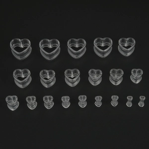 Detailed arrangement of transparent acrylic heart ear gauges in various sizes on black background