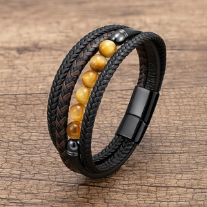Detail of multi-layer braided leather bracelet with tiger eye stones on wood background