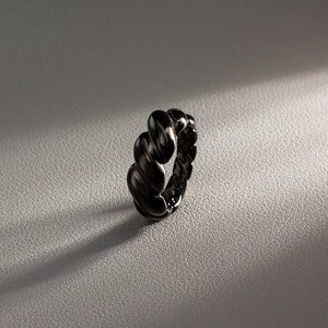 Macro shot of minimalist black croissant dome ring with twisted spiral texture