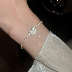 Close-up of sparkling heart pendant on a gold-plated tennis bracelet with zircon